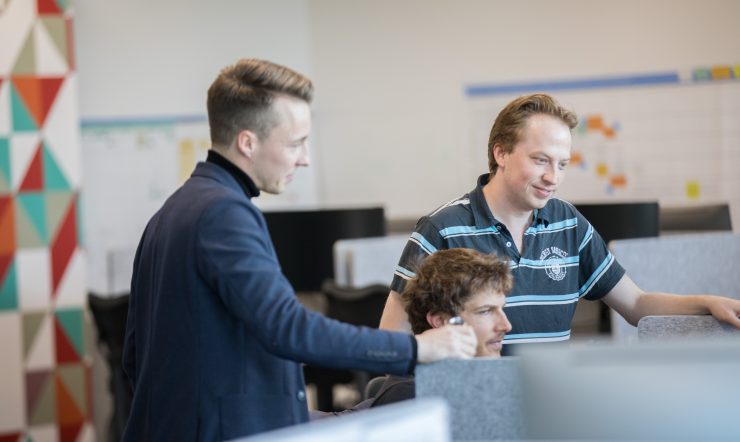 Three men crowded around a computer