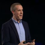 Peter Maynard staat op een podium en geeft een presentatie.