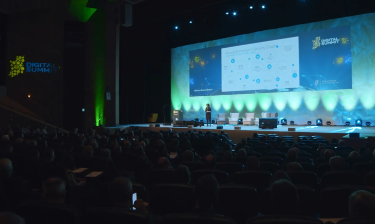 a crowd of people in a dark room listening to a presentation