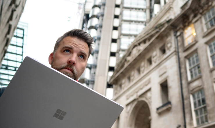 Man loopt met Surface device over straat