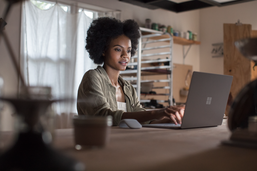 Female working on project using Microsoft Surface Laptop (platinum) in a ceramic workshop