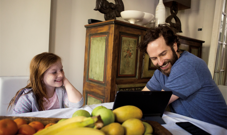 Father and daughter at dining room table on laptop; Photographer: Bobo Olsson