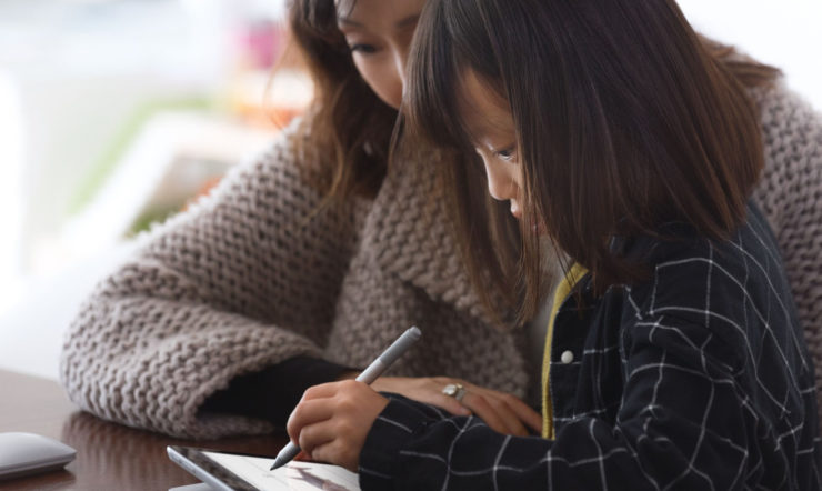una donna e un bambino seduti a un tavolo che utilizzano un laptop