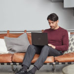 a person sitting on a sofa using a laptop