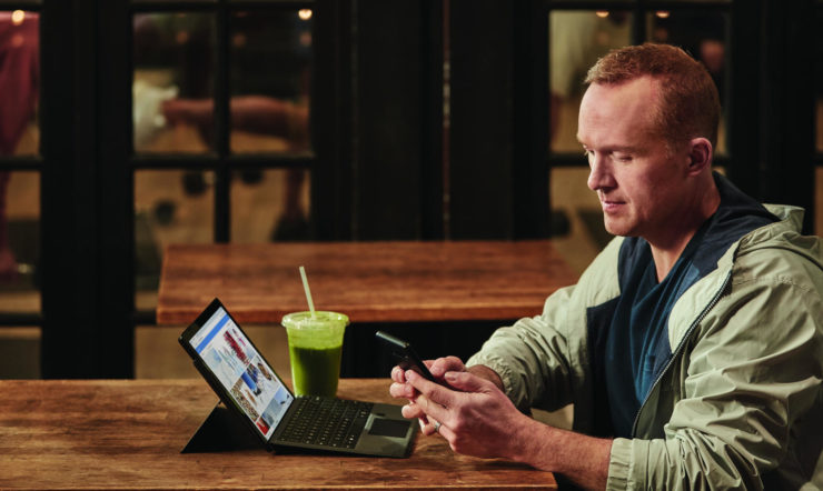 en mand sidder ved et bord og bruger en laptop
