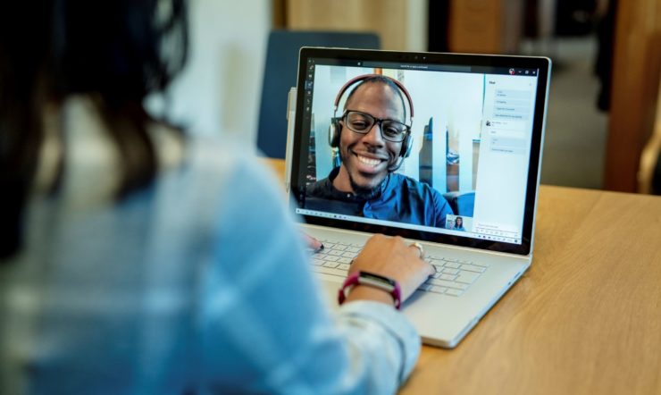 een persoon die een laptopcomputer gebruikt die bovenop een lijst zit
