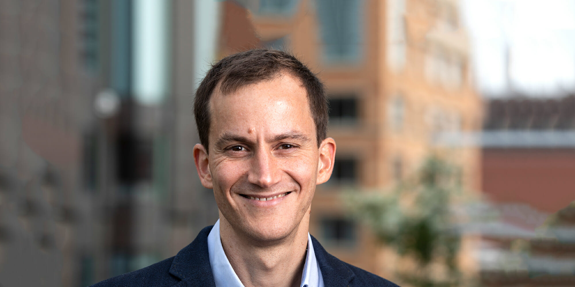 a man wearing a suit and tie smiling at the camera