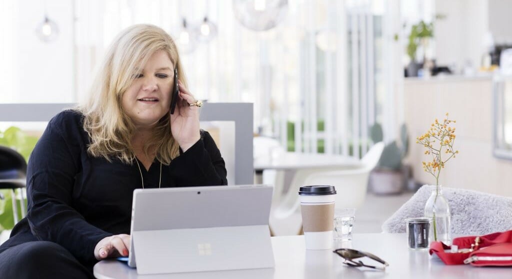en kvinde sidder ved et bord ved hjælp af en bærbar computer