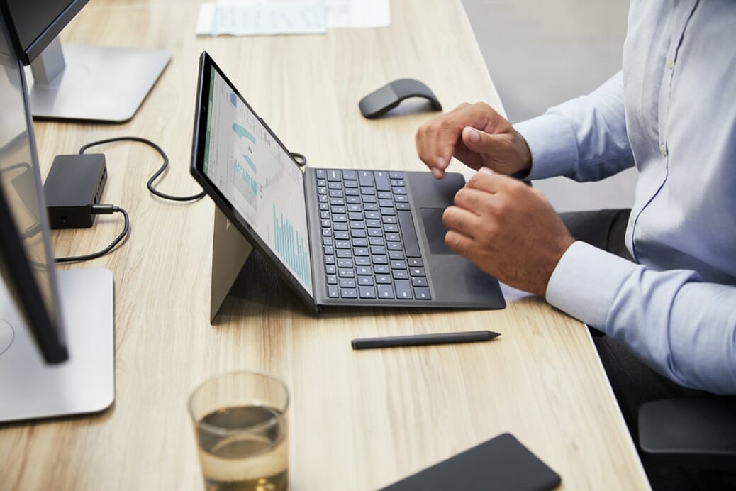 een mens die een laptopcomputer gebruikt die bovenop een houten lijst zit
