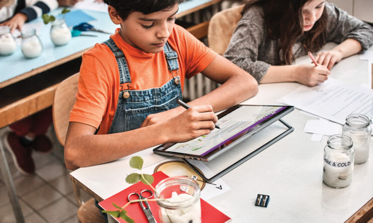 een groep mensen die aan een lijst met behulp van een laptop zitten