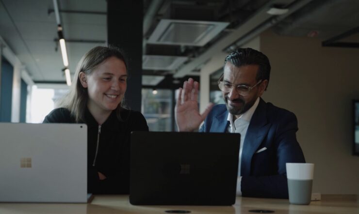 Kvinna och man framför varsin laptop har ett möte med andra via Teams Rum