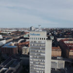 Aerial view of a cityscape with a tall office building featuring the Folksam logo prominently in the foreground.