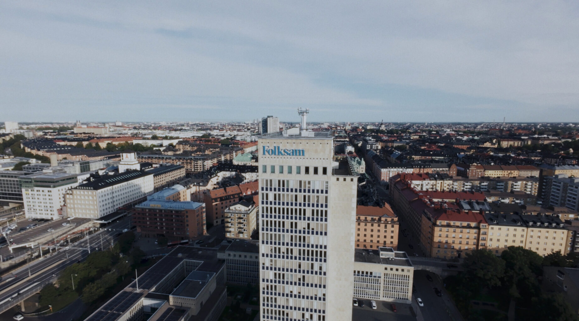 Aerial view of a cityscape with a tall office building featuring the Folksam logo prominently in the foreground.