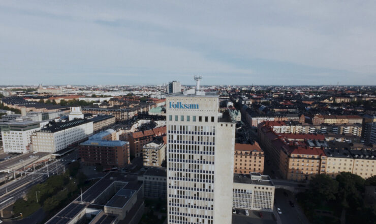 Aerial view of a cityscape with a tall office building featuring the Folksam logo prominently in the foreground.