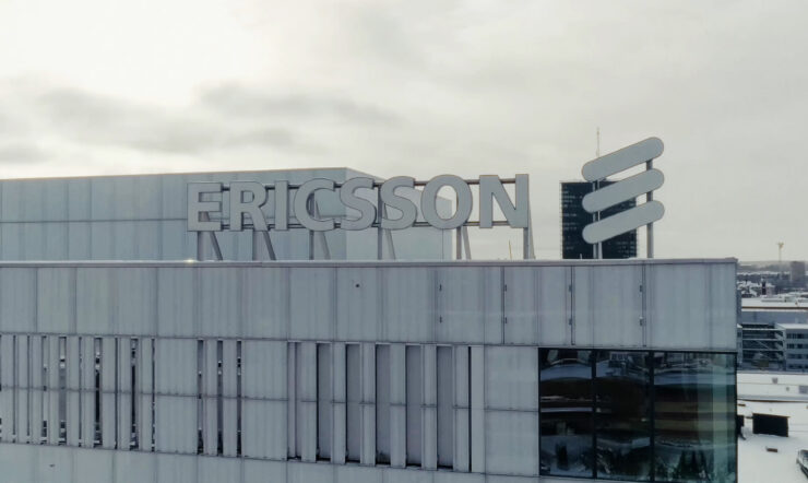 Ericssons logotyp på taket till en stor kontorsbyggnad under en mulen himmel.